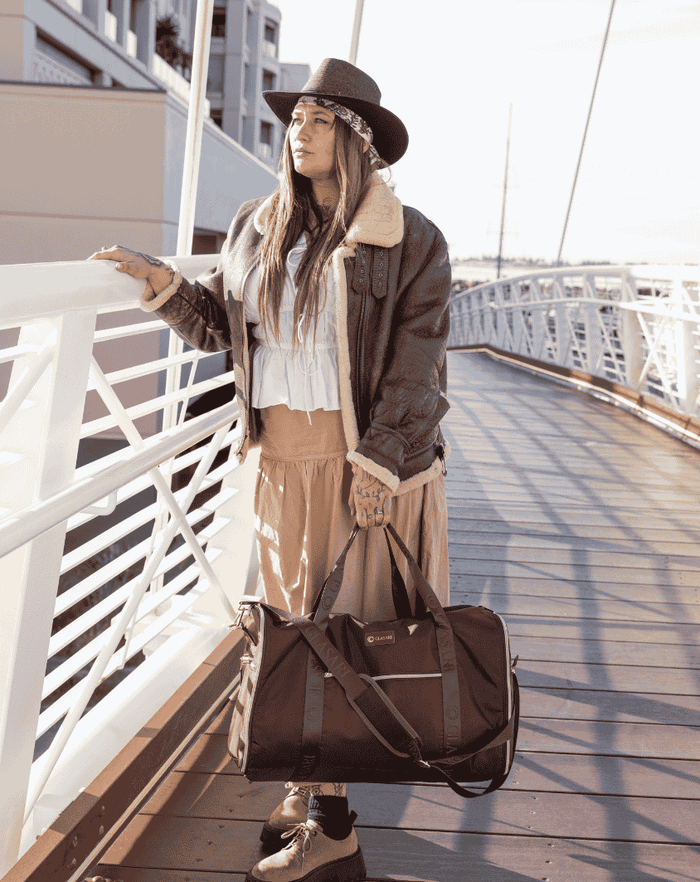 A traveller on a boardwalk with a GLASARI duffle at her feet