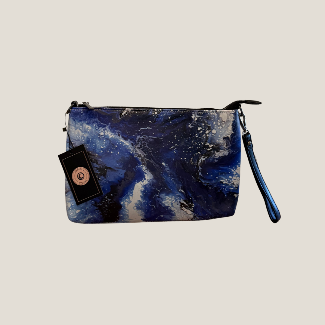 GLASARI Art Cross-Body Bag in Ocean Swirl, a deep blue and white marbled artwork, with GLASARI swing tag and wrist strap