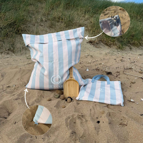 GLASARI Beach Buddy Vault in Blue Horizon stripe filled with sand, with close-ups of the combination lock and the D-ring for attaching a dog lead or sunshade, plus the matching carry bag and free bamboo scoop