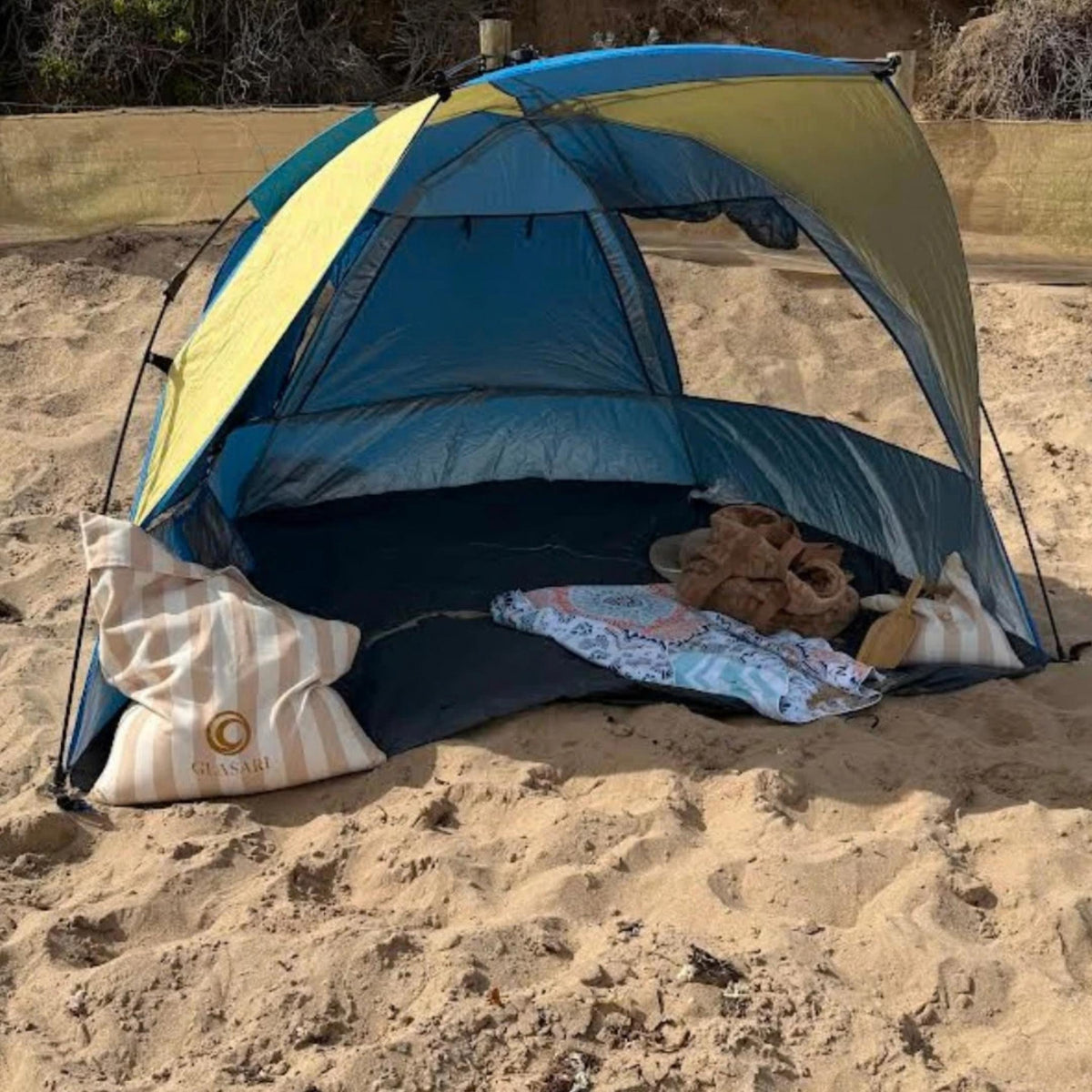 GLASARI Beach Buddy Vault in Coastal Sand stripe filled with sand, anchoring a beach shade tent on the sand