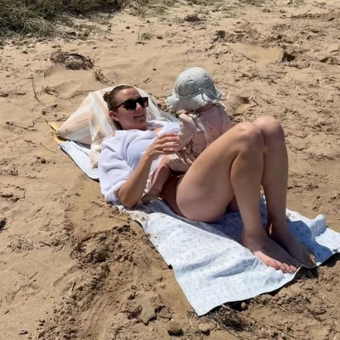 A mum and baby relaxing on the beach beside their Beach Buddy Vault