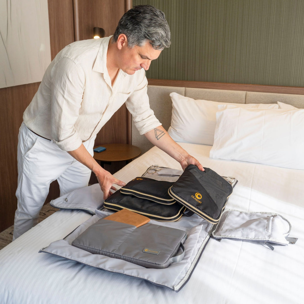 GLASARI Compressi-Cubes in Classic Black being packed into the open Retreat Duffle on a hotel bed
