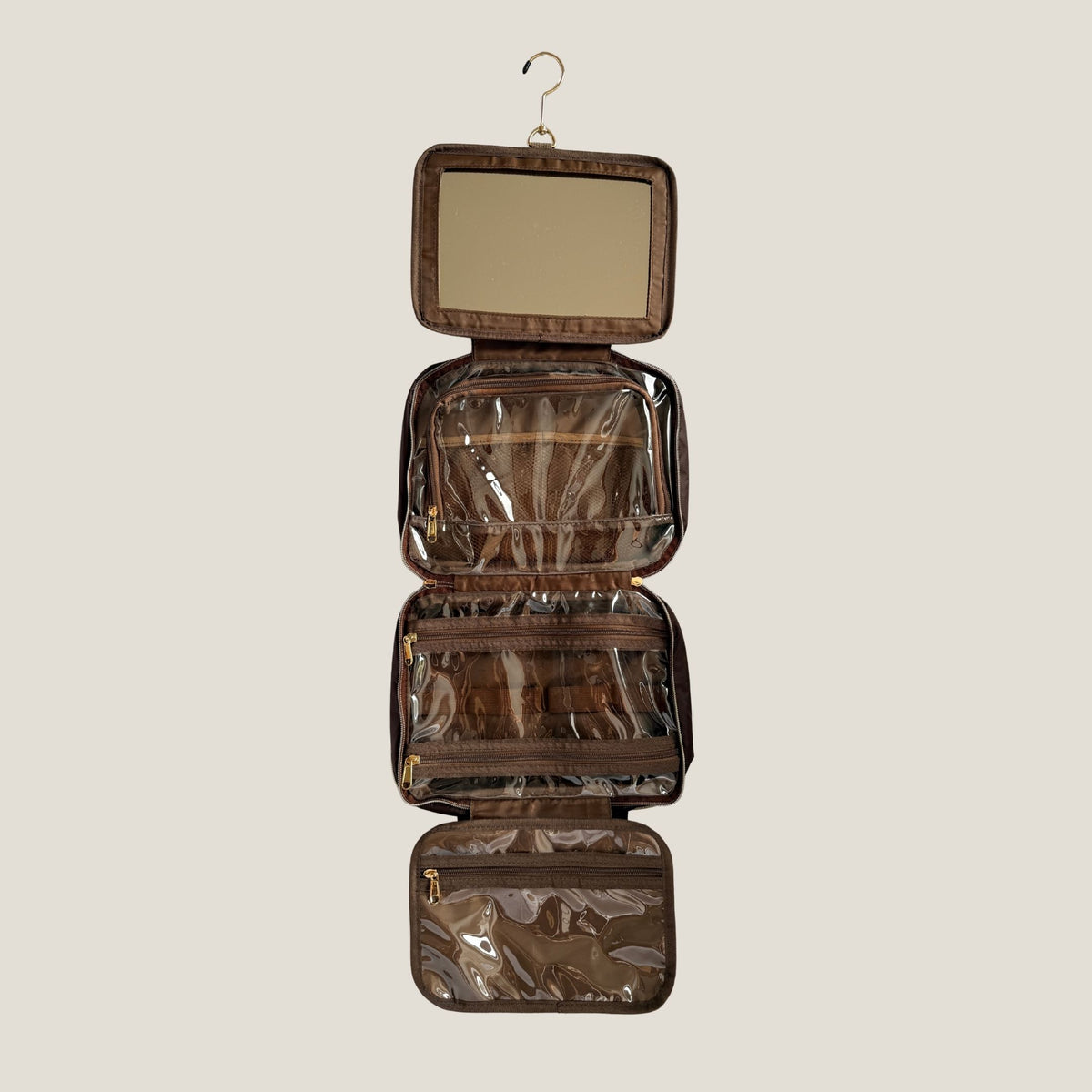 GLASARI On-The-Glow Cosmetic Case in Cocoa Drift hanging fully unfolded, showing the built-in mirror, clear zip pockets and hanging hook