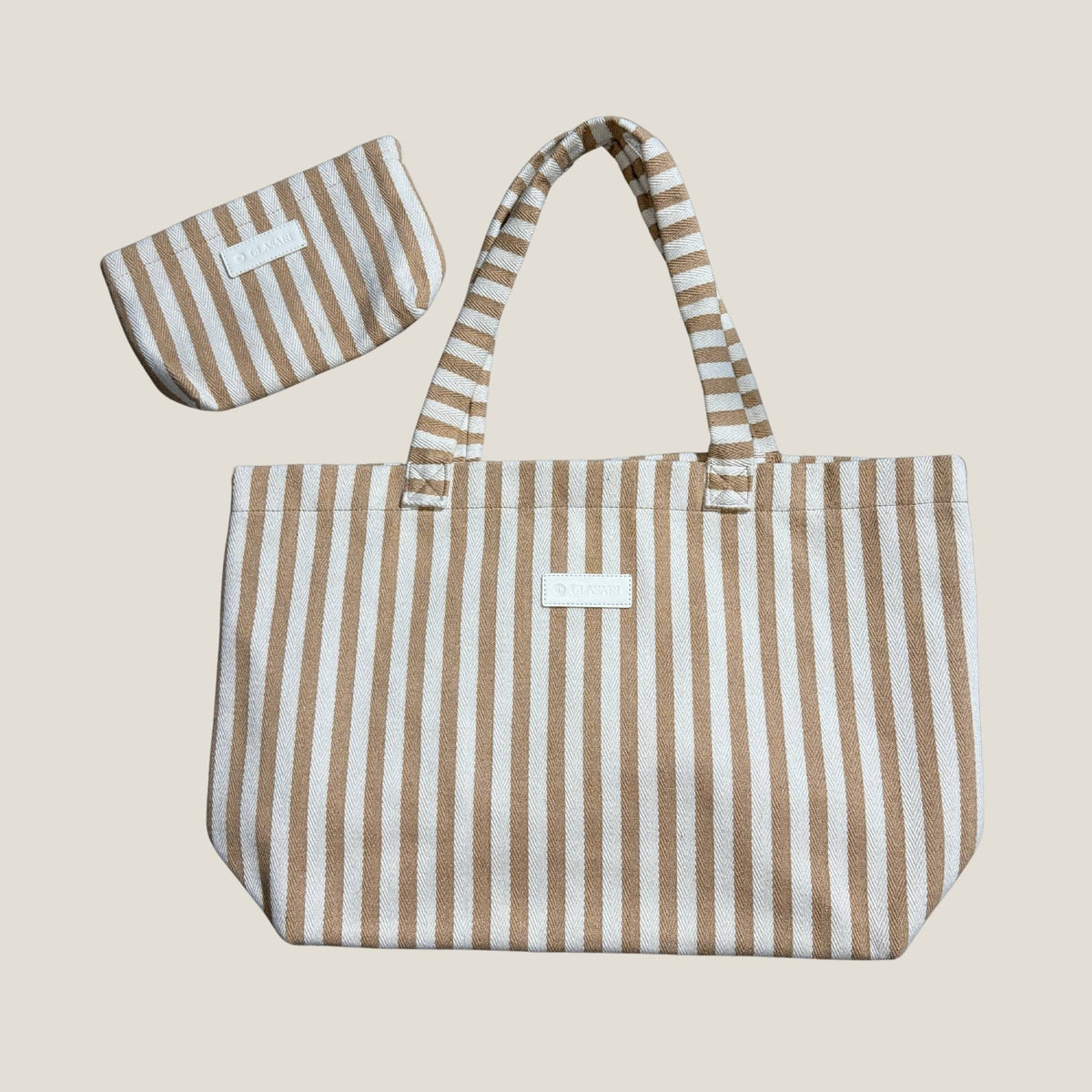 Flat lay of the GLASARI Shore Tote in Sand Dune Stripe and its matching zip pouch, showing the full tote shape and herringbone cotton stripes