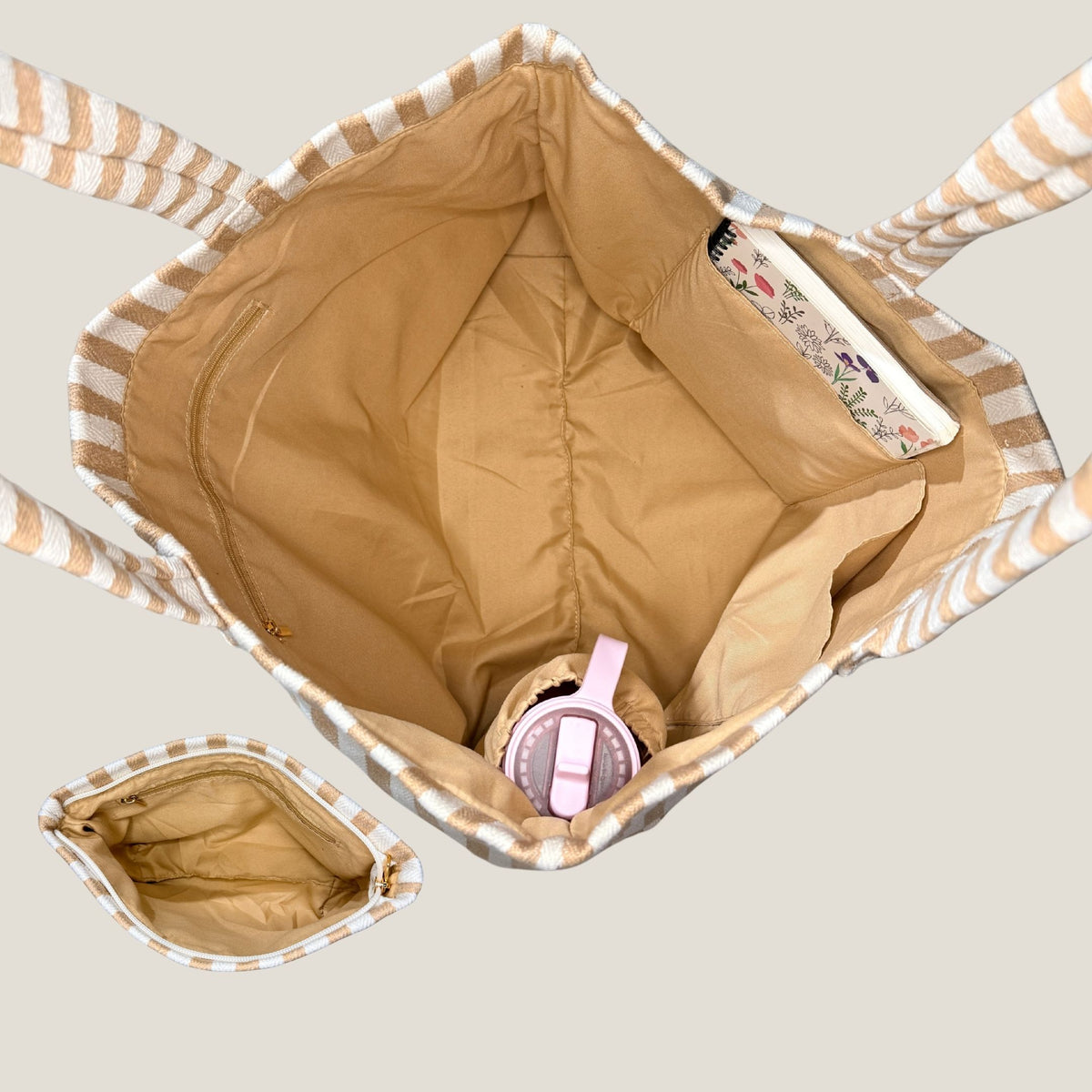 Inside view of the GLASARI Shore Tote in Sand Dune Stripe showing the tan lining, zip pocket, slip pocket holding a book and water bottle holder